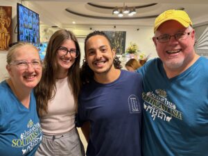 Four team members smiling, arm and arm