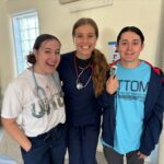 Three nurses standing together and smiling at the camera